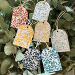 Decorative seed paper tags with floral patterns hanging among green leaves