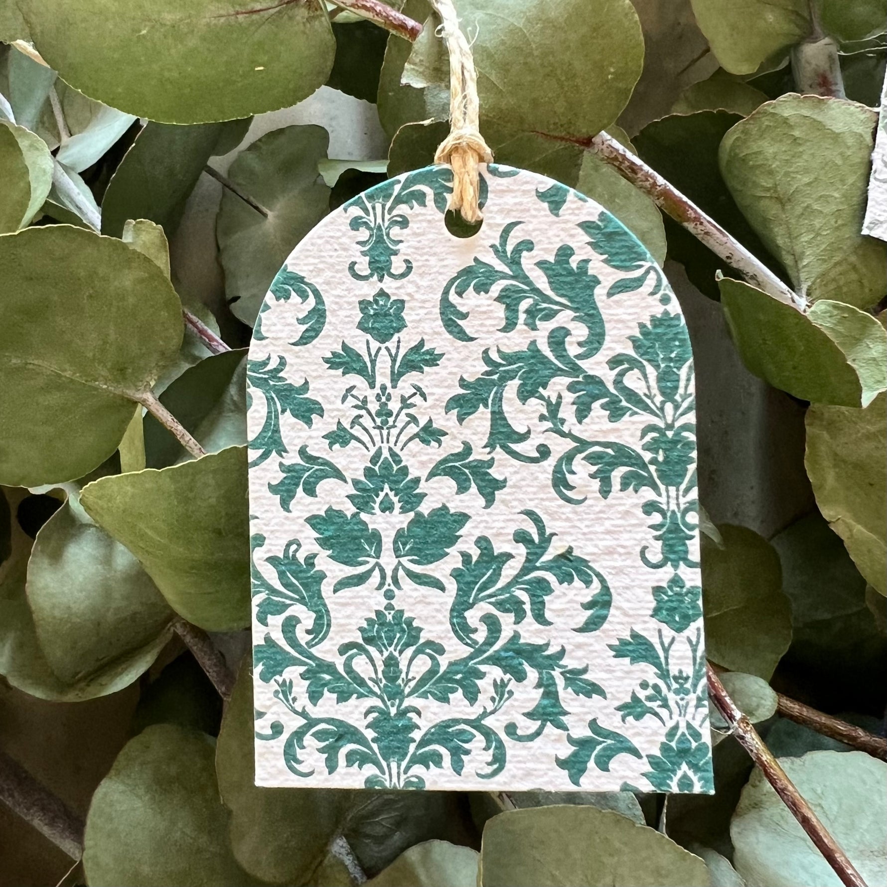 Seed paper green and white patterned tag hanging among green leaves
