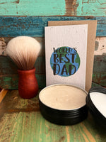 A handmade gift set featuring a 'World's Best Dad' seed paper greeting card with a kraft envelope, a black tin of shaving soap, and a Australian Jarrah hardwood shaving brush