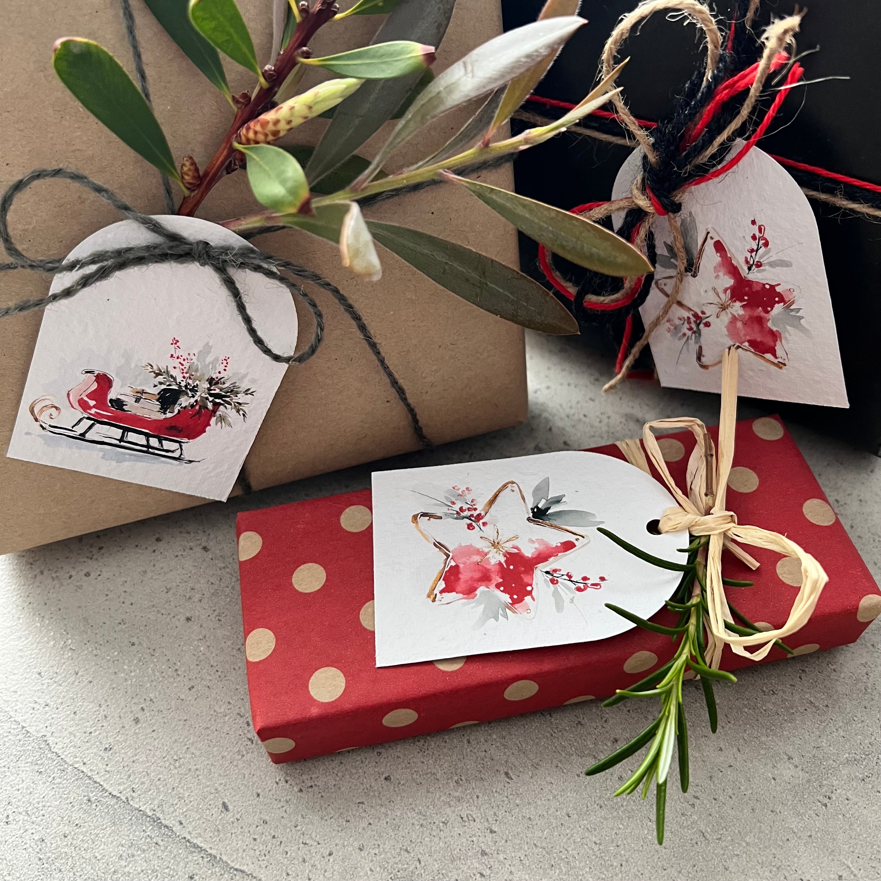 Two gift boxes, one brown and one red with white polka dots, tied with decorative strings and featuring watercolor plantable tags.