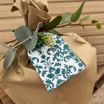 Gift wrapped in brown paper with a plantable tag and greenery on a wooden surface