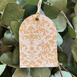 Plantable brown and white patterned tag hanging among green leaves