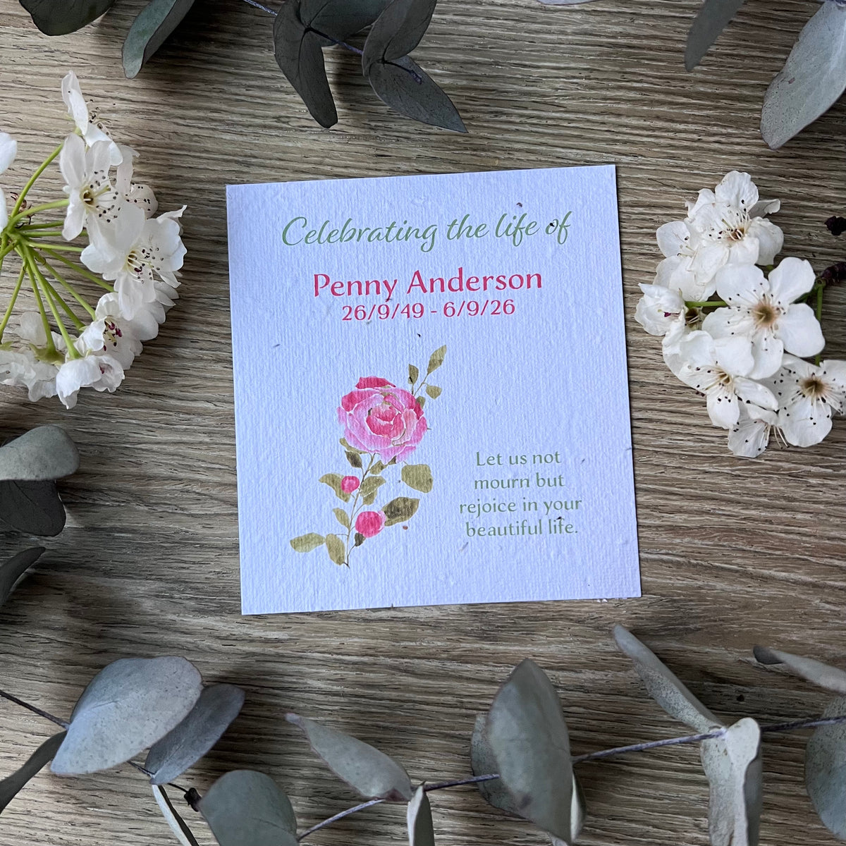 A seed paper memorial card with a pink rose illustration and printed text.