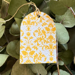 Decorative yellow and white patterned tag hanging among green leaves