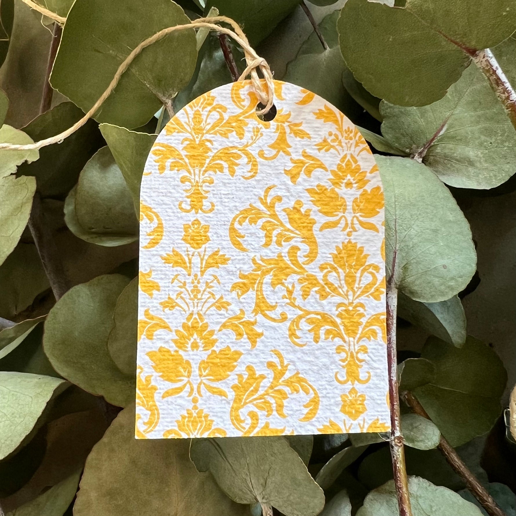 Decorative yellow and white patterned tag hanging among green leaves