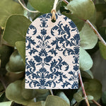 Plantable tag with blue floral pattern hanging among green leaves