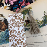 Plantable bookmark with brown damask pattern on an open book page.