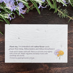 Card with flower seeds embedded in plantable paper on a wooden surface.