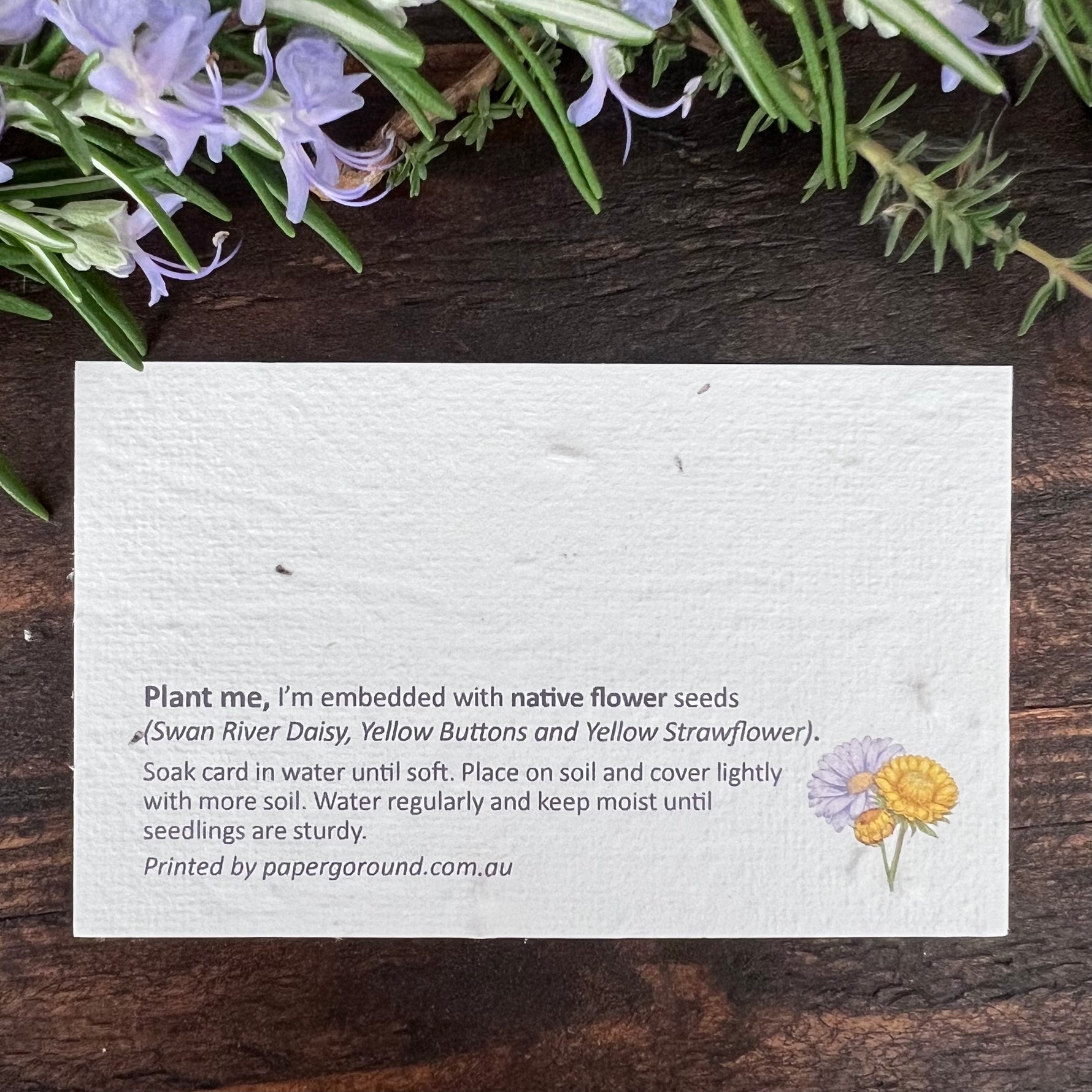Card with flower seeds embedded in plantable paper on a wooden surface.