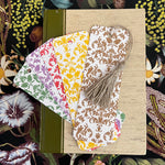 Plantable bookmarks with floral patterns on a textured surface surrounded by floral illustrations.