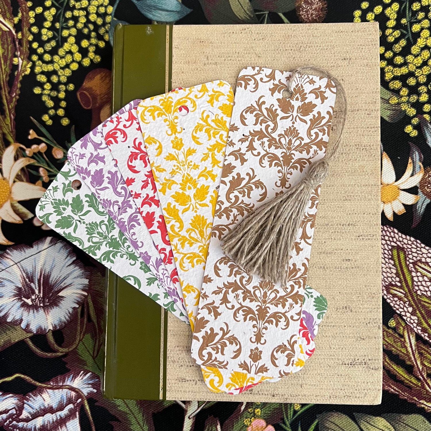 Plantable bookmarks with floral patterns on a textured surface surrounded by floral illustrations.