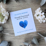 Seed paper memorial card with blue text and a blue heart illustration.